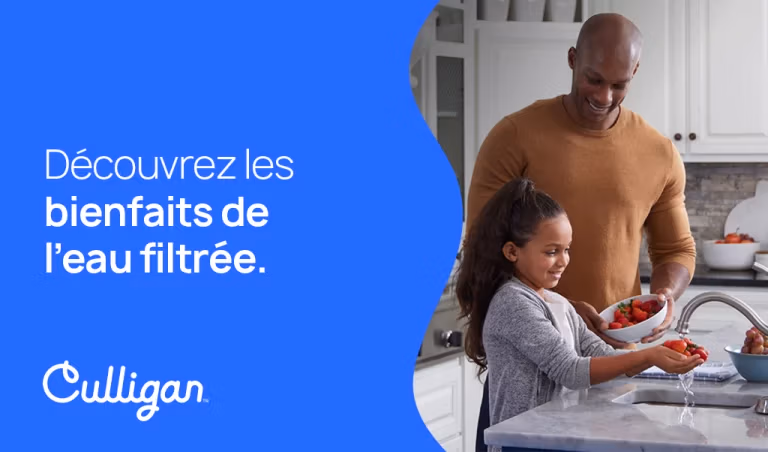 Un père regarde sa petite fille laver des fraises avec l'eau du robinet de la cuisine